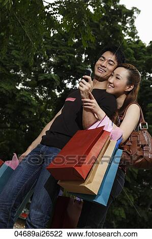 Stock Image - Chinese couple shopping and looking at phone. Fotosearch