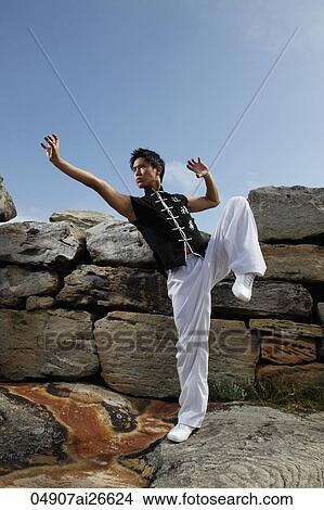 Picture - Chinese man doing martial arts on rocks. Fotosearch