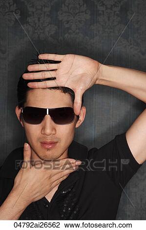 Stock Image - Chinese man framing face with his hands. Fotosearch