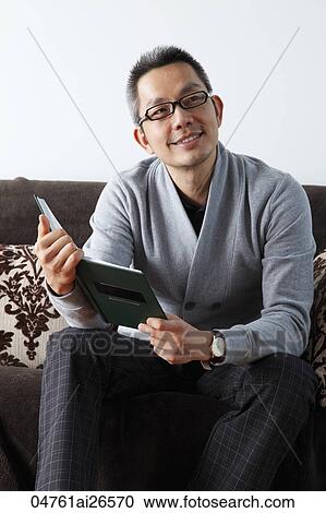 Stock Image - Chinese man holding a book and looking away. Fotosearch