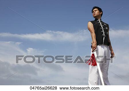 Stock Photo - Chinese man holding a sword and looking at sky. Fotosearch