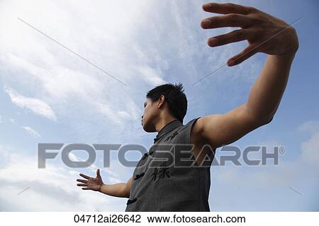 Stock Image - Chinese man holding his arms out, doing martial arts.. Fotosearch