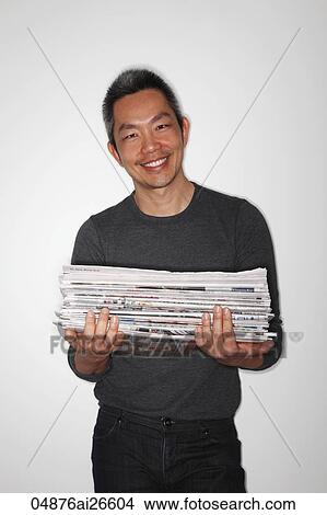 Picture - Chinese man holding newspapers ready to recycle. Fotosearch
