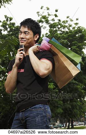 Chinese man holding shopping bags and thinking View Large Photo Image Stock Photograph - Chinese man holding shopping bags and thinking. Fotosearch