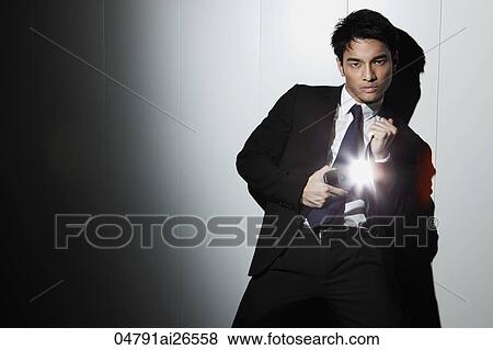 Stock Photo - Chinese man in a business suit taking a photo with his camera flash.. Fotosearch