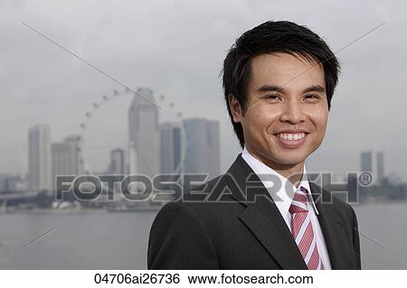Chinese man in suit standing in front of city skyline, smiling View Large Photo Image Stock Photograph - Chinese man in suit standing in front of city skyline, smiling. Fotosearch