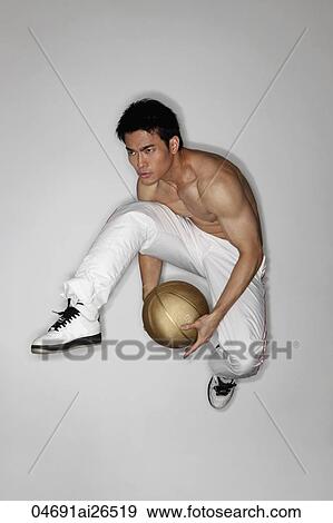 Stock Photo - Chinese man jumping in air holding a basketball. Fotosearch