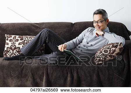 Stock Photo - Chinese man relaxing on sofa relaxing. Fotosearch