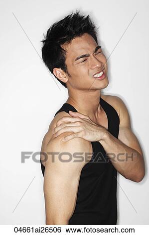 Stock Photograph - Chinese man rubbing his shoulder in pain. Fotosearch
