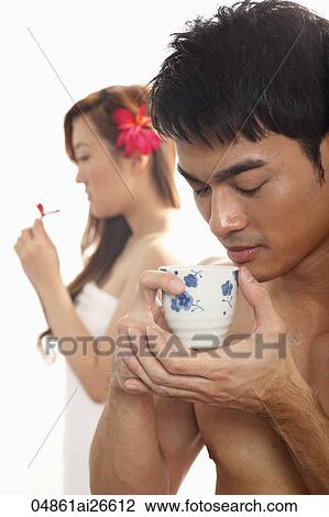 Chinese man sipping tea while woman smells flower in background View Large Photo Image Stock Image - Chinese man sipping tea while woman smells flower in background. Fotosearch