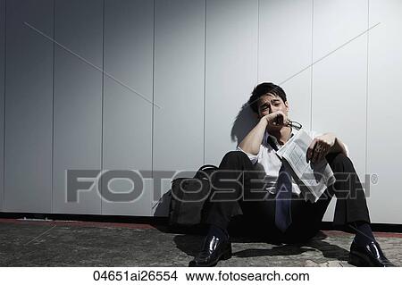 Chinese man sitting on ground holding newspaper and looking sad View Large Photo Image Picture - Chinese man sitting on ground holding newspaper and looking sad. Fotosearch