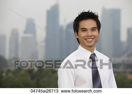 Stock Image - Chinese man standing in front of city skyline. Fotosearch