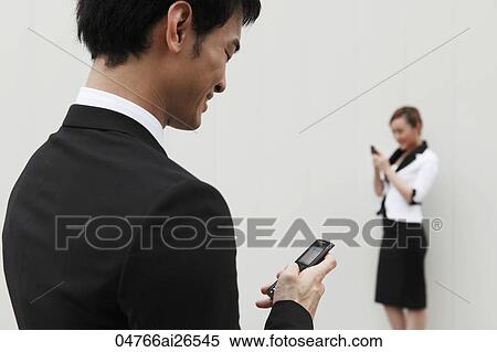 Stock Photography - Chinese man texting woman with hand phone. Fotosearch