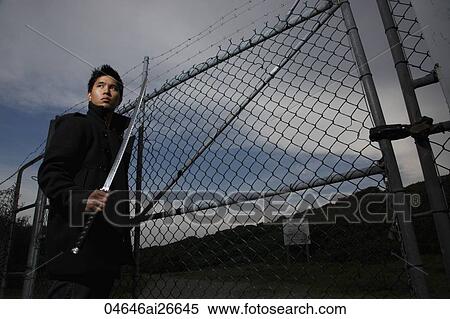 Chinese man walking near fence holding a sword View Large Photo Image Stock Photography - Chinese man walking near fence holding a sword. Fotosearch