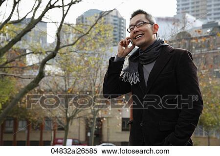Chinese man walking outside while talking on the phone View Large Photo Image Stock Photography - Chinese man walking outside while talking on the phone. Fotosearch