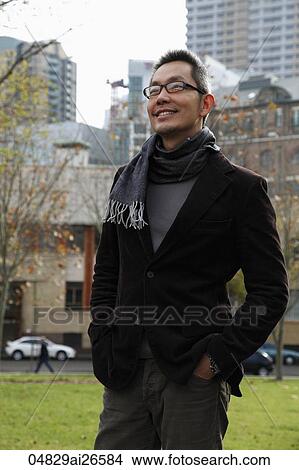 Picture - Chinese man wearing a scarf and jacket outside and smiling. Fotosearch