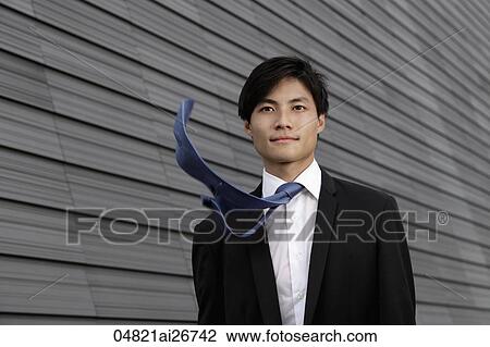 Stock Image - Chinese man wearing a suit with tie blowing in the wind. Fotosearch