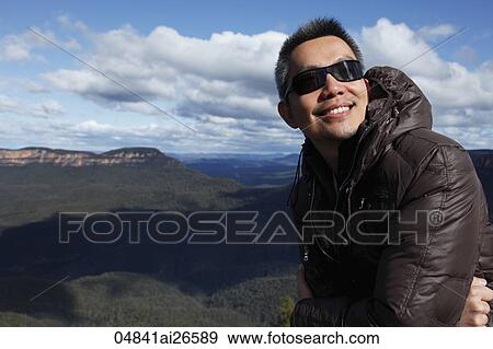 Chinese man wearing jacket smiling in front of mountain range View Large Photo Image Stock Photo - Chinese man wearing jacket smiling in front of mountain range. Fotosearch