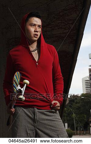 Chinese man wearing red hooded sweatshirt and holding skateboard outside View Large Photo Image Stock Image - Chinese man wearing red hooded sweatshirt and holding skateboard outside. Fotosearch