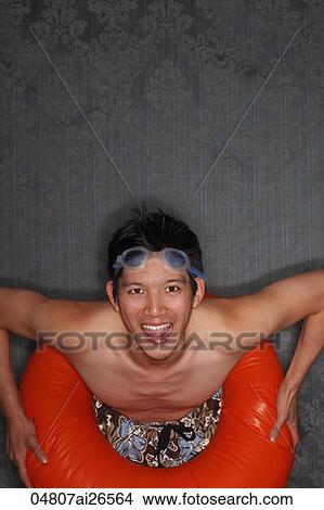 Chinese man wearing swim suit and orange inner tube around his waist View Large Photo Image Picture - Chinese man wearing swim suit and orange inner tube around his waist. Fotosearch