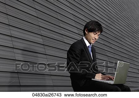 Chinese man working on lap top in front of building View Large Photo Image Stock Image - Chinese man working on lap top in front of building. Fotosearch