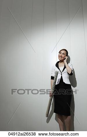 Stock Photo - Chinese woman holding building plans and talking on phone. Fotosearch