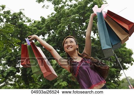 Picture - Chinese woman holding shopping bags in the air. Fotosearch
