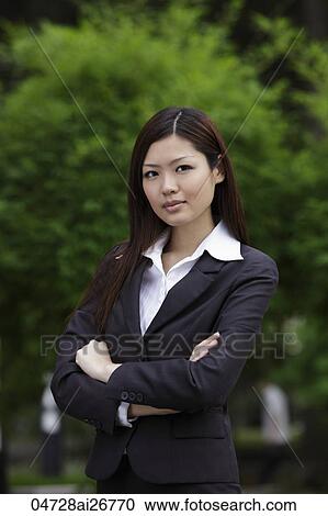 Stock Image - Chinese woman looking at camera with arms folded. Fotosearch