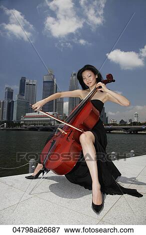 Chinese woman playing cello outside in front of buildings View Large Photo Image Stock Photo - Chinese woman playing cello outside in front of buildings. Fotosearch