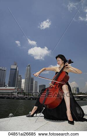 Stock Photography - Chinese woman playing cello outside in front of buildings. Fotosearch