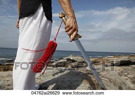 Stock Photo - Cropped shot of man holding a sword.. Fotosearch