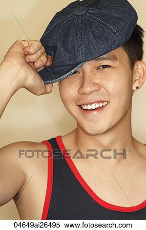 Stock Photography - Head shot of Chinese man holding hat and smiling. Fotosearch