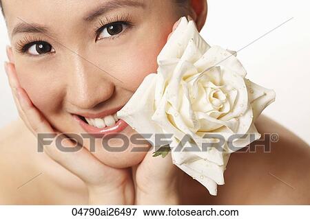 Stock Photo - Head shot of Chinese woman holding flower. Fotosearch