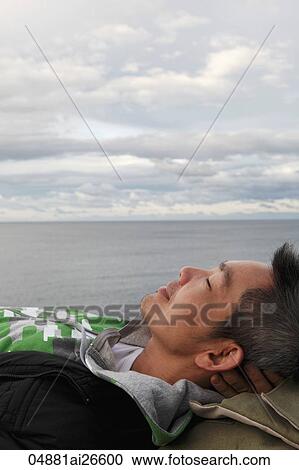 Head shot of man lying down on ground with ocean in background View Large Photo Image Stock Image - Head shot of man lying down on ground with ocean in background. Fotosearch