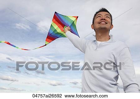 Man flying colourful kite and smiling View Large Photo Image Stock Image - Man flying colourful kite and smiling. Fotosearch