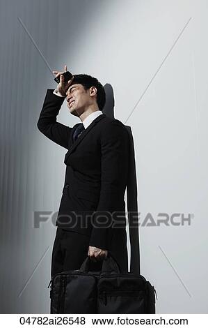 Stock Photo - Man in business suit wiping his brow and frowning. Fotosearch