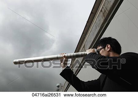 Stock Image - Man looking through building plans like a telescope. Fotosearch