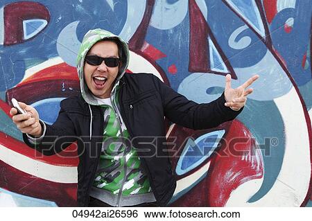 Man making hand gestures in front of graffiti painted wall View Large Photo Image Stock Photograph - Man making hand gestures in front of graffiti painted wall. Fotosearch