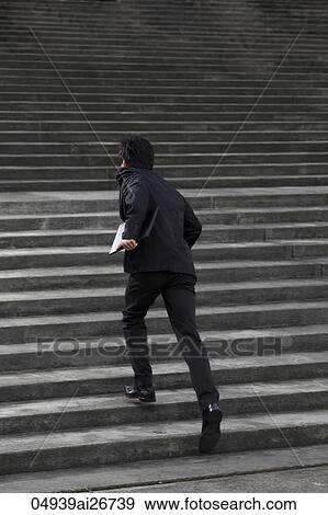 Stock Photo - Man running up stairs wearing a suit. Fotosearch