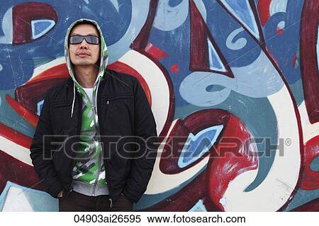 man wearing hooded sweatshirt standing in front of graffiti painted wall View Large Photo Image Stock Photography - man wearing hooded sweatshirt standing in front of graffiti painted wall. Fotosearch