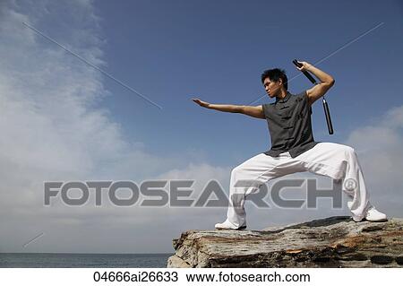 Profile of man standing on rocks holding nunchucks View Large Photo Image Stock Image - Profile of man standing on rocks holding nunchucks. Fotosearch