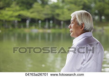 Stock Image - Profile of older man looking at lake. Fotosearch