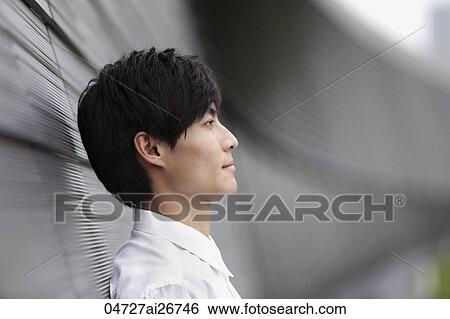 Stock Photograph - Profile shot of man leaning against wall. Fotosearch