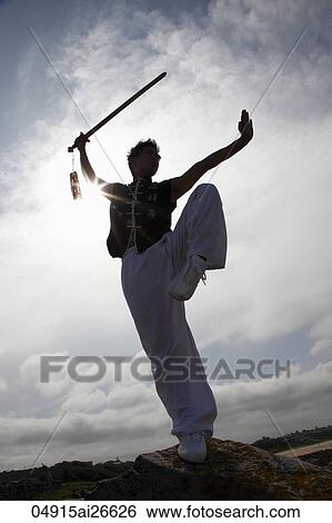 Stock Photograph - Silhouette of man doing martial arts with a sword. Fotosearch