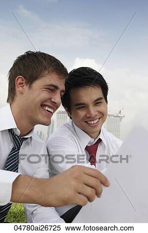 Two business men smiling and looking at paper View Large Photo Image Stock Photography - Two business men smiling and looking at paper. Fotosearch