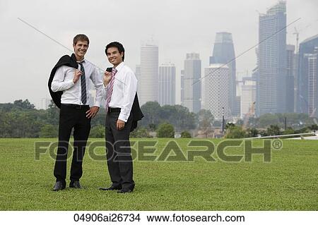 Picture - Two men holding their jackets over their shoulders outside. Fotosearch