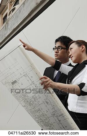Stock Image - Two people looking at building plans. Fotosearch