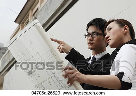 Two people looking at building plans View Large Photo Image Stock Photo - Two people looking at building plans. Fotosearch