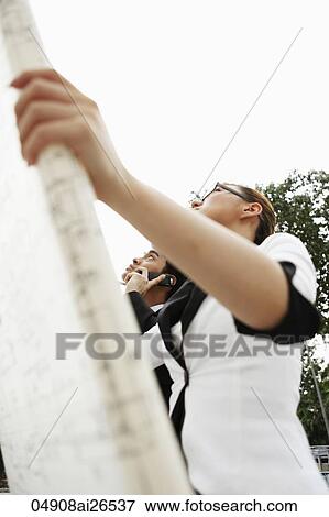 Two people looking up and holding building plans View Large Photo Image Stock Photo - Two people looking up and holding building plans. Fotosearch