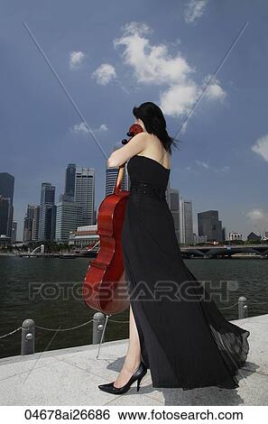 Woman holding cello and looking at city skyline View Large Photo Image Stock Photograph - Woman holding cello and looking at city skyline. Fotosearch